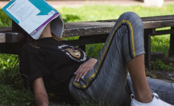 A girl sleeping on a bench open-air