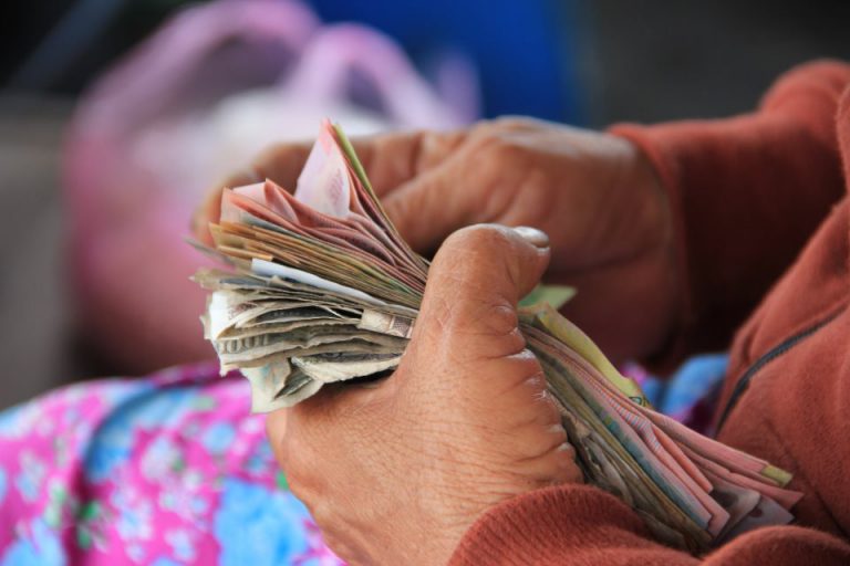 The hands of an old lay counting money
